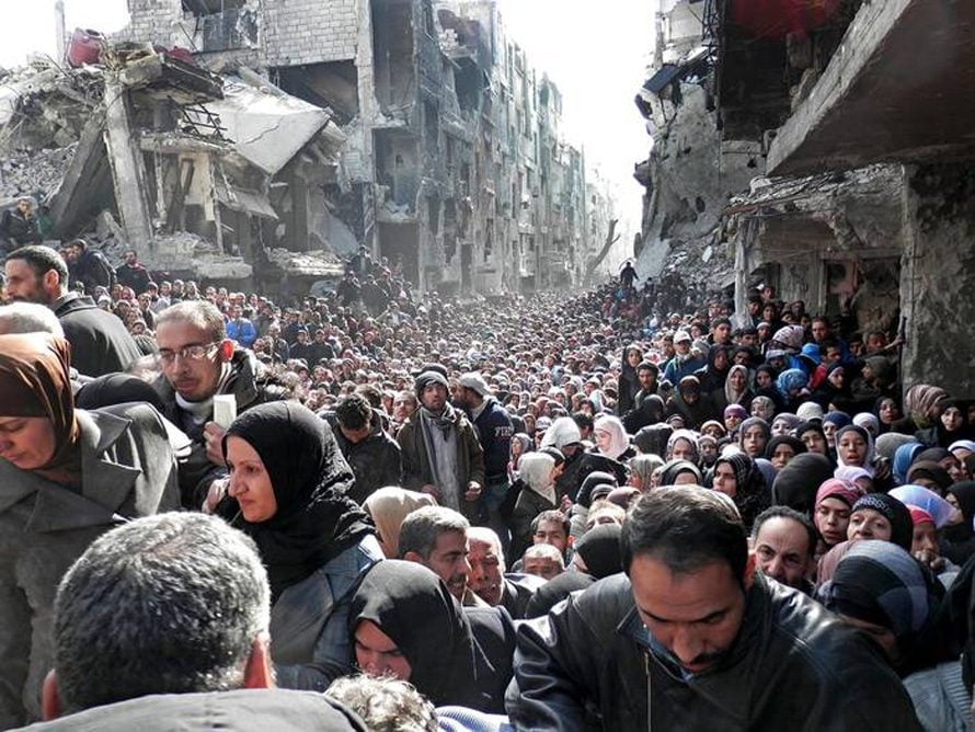 Residents of the besieged Yarmouk camp south of Damascus wait to receive food aid distributed by the UN 