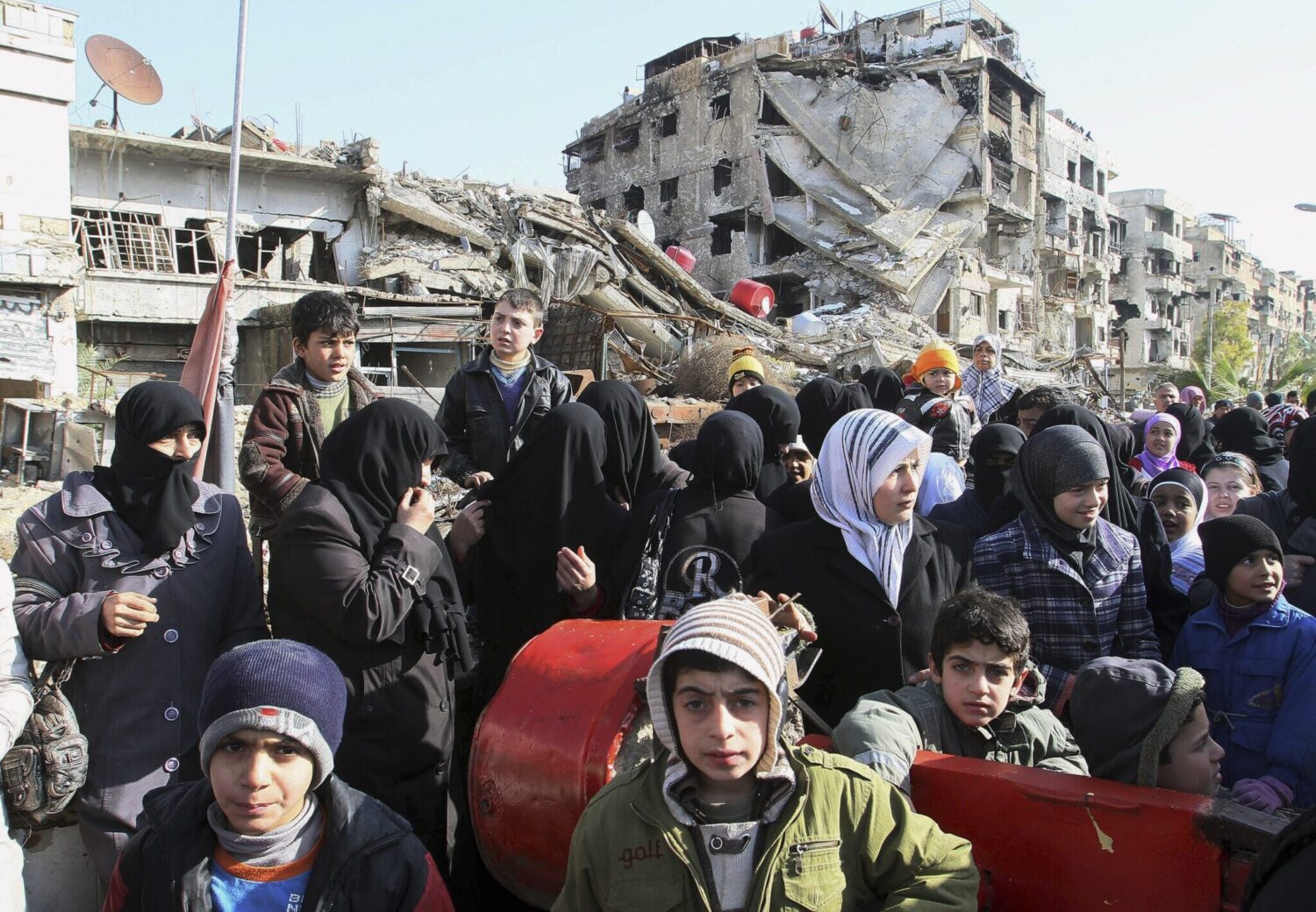 Hundreds of Syrians wait in line at a military checkpoint