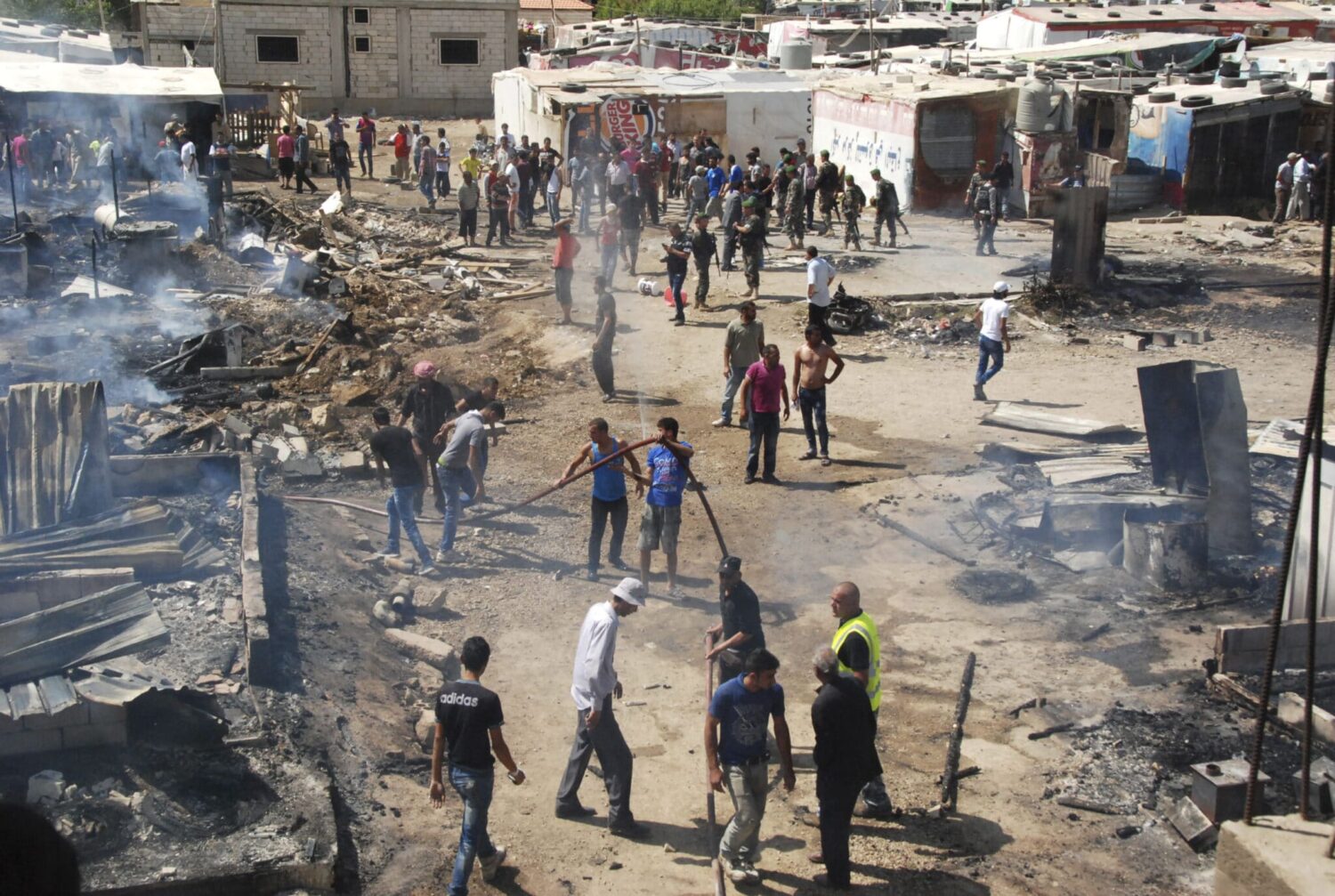 Syrian refugees estinguish a fire in a camp in Lebanon