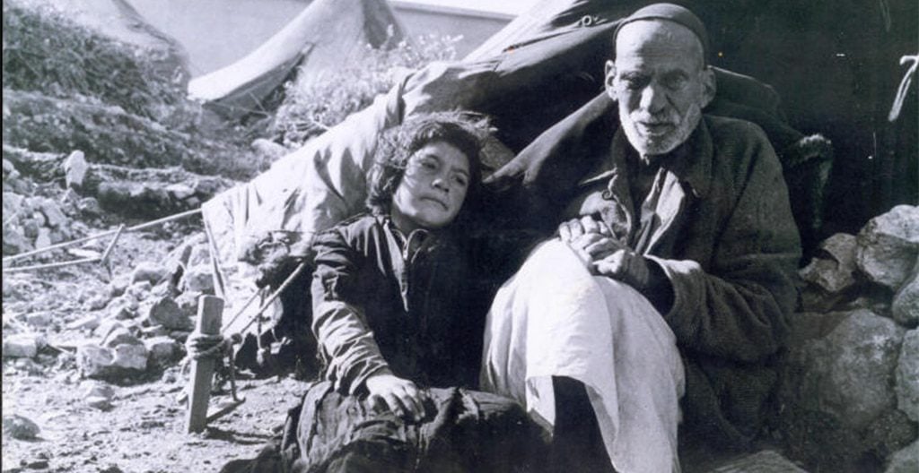 Old man and small girl during nakba sitting next to a tent, Palestinian Refugees.