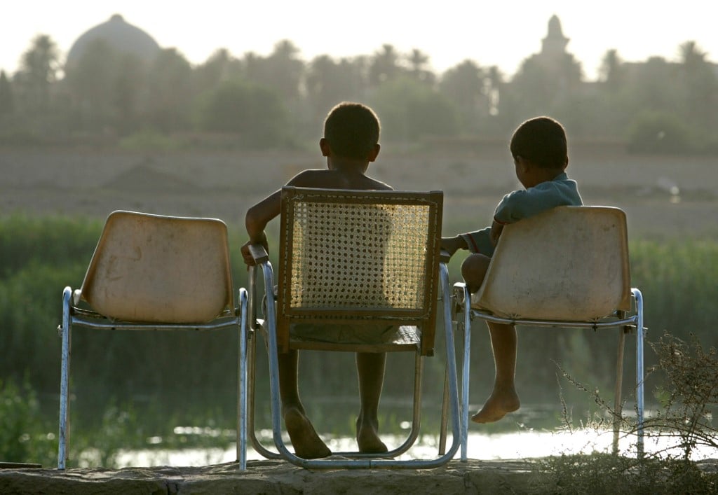 Two Iraqi children sit at sunset on the banks of the Tigris river in Iraq