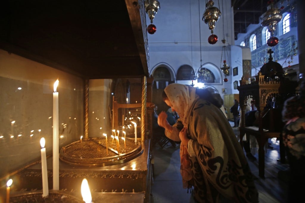 A Christian pilgrim lights a candle as she visits the Church of the Nativity