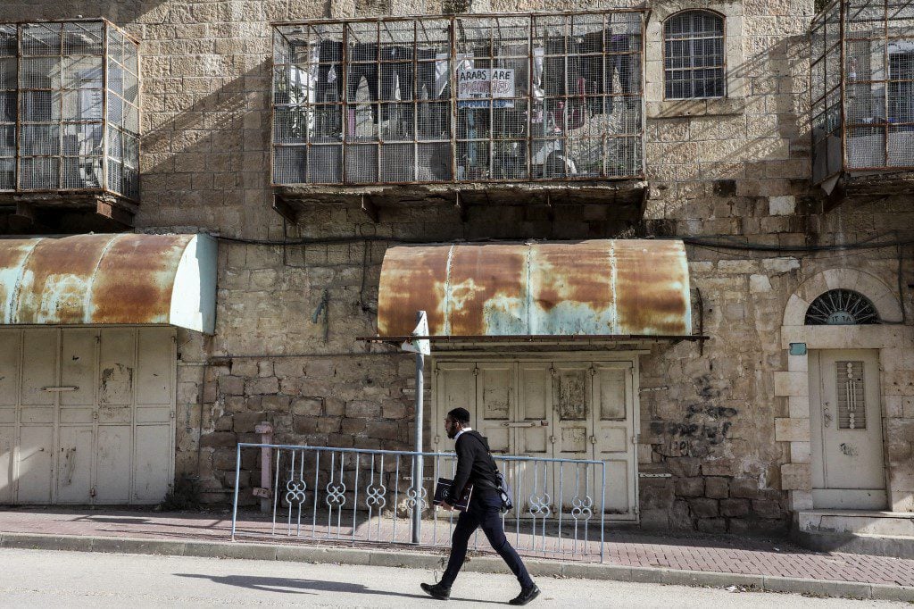 man walking near a wall in Israeli controlled street