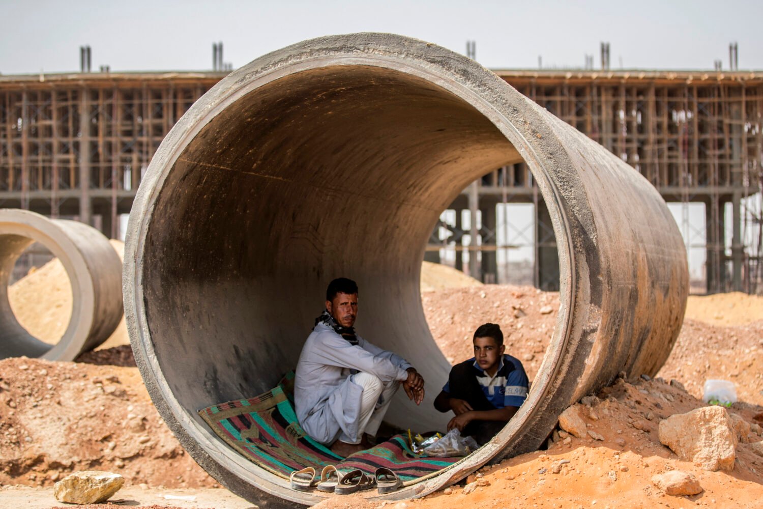 Labourers rest and have a meal inside a concrete tube