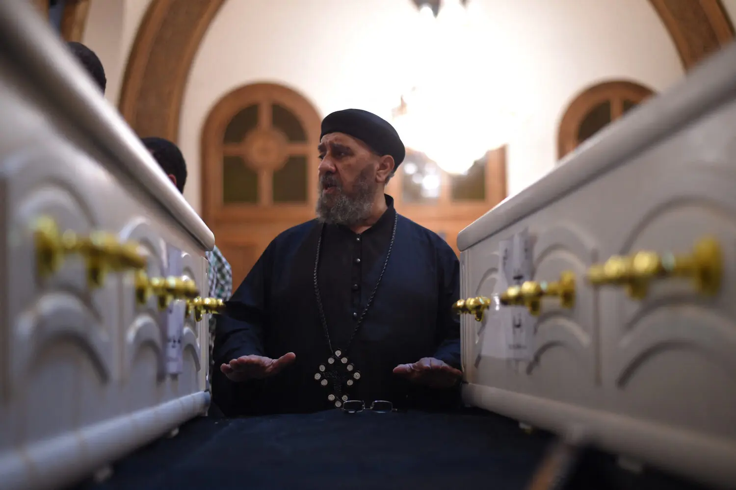 A Coptic priest blesses the coffins of victims