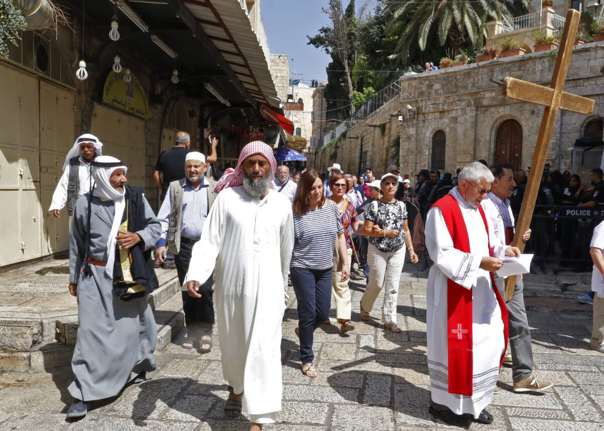 A group of Christian pilgrims walk near Muslim worshippers in Jerusalem's old city.