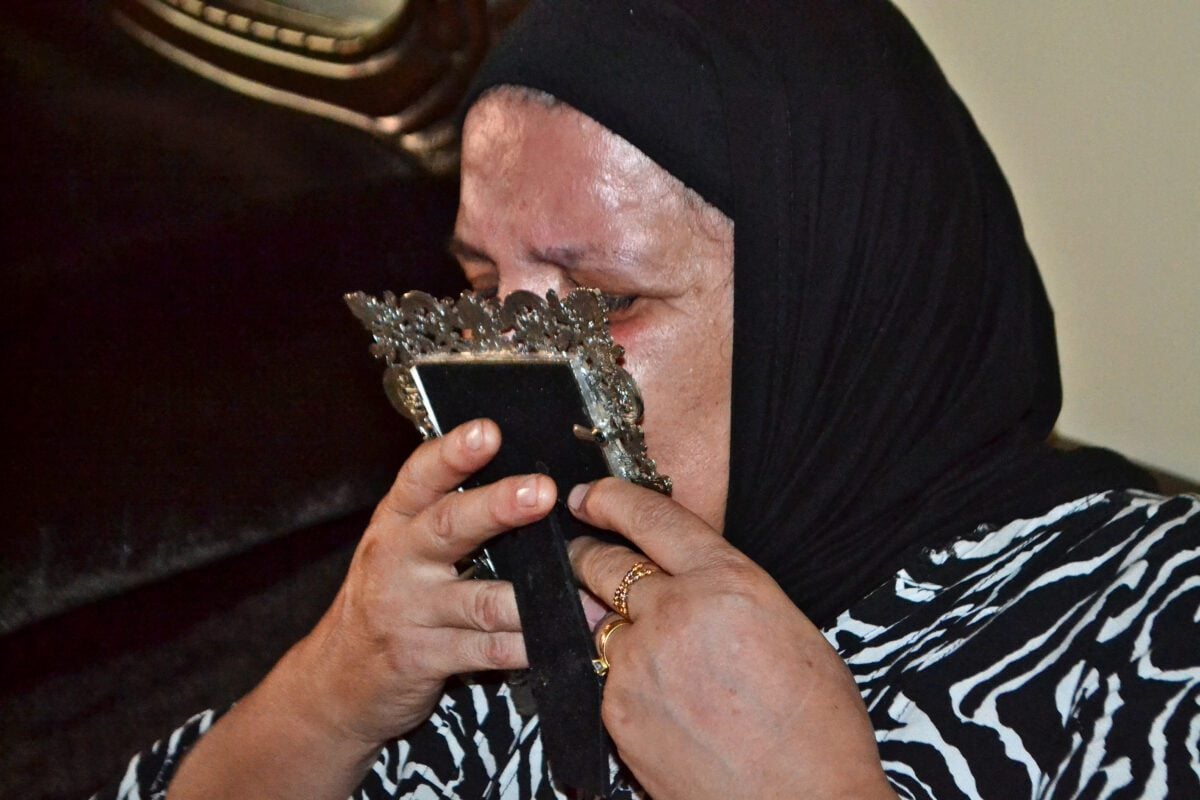 A woman reacts on September 23, 2022, in the northern Lebanese city of Tripoli as she kissed the photograph of her son.